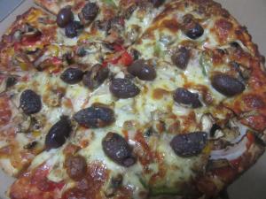 eine Pizza mit Oliven und Käse auf dem Tisch in der Unterkunft Dampier Mermaid Hotel Karratha in Dampier
