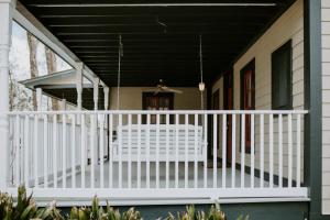 um alpendre com um corrimão branco e um telhado preto em Maison Mouton Bed & Breakfast em Lafayette