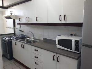 a kitchen with a microwave and a sink at Campanario 104 con factura in Iquique