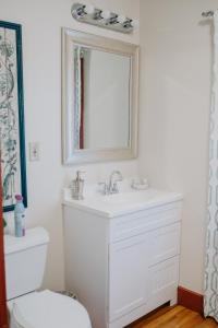 La salle de bains est pourvue d'un lavabo blanc et d'un miroir. dans l'établissement Maison Mouton Bed & Breakfast, à Lafayette