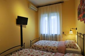 una camera con due letti e una finestra con tv di Casa Max a Napoli