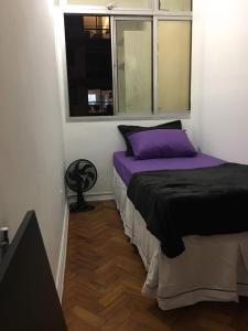 Un dormitorio con una cama con sábanas moradas y una ventana. en Adonai Copacabana 01, en Río de Janeiro