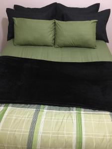 a bed with black and green sheets and pillows at Adonai Copacabana Rooms 01 in Rio de Janeiro