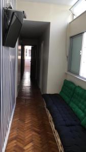 sala de estar con sofá verde y ventana en Adonai Copacabana Rooms 01, en Río de Janeiro