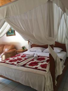 a bed with a red and white blanket on it at Barclona Guesthouses Lovina in Pabean Buleleng