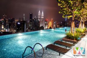 a large swimming pool with a city skyline at night at Expressionz Suites, 300mbps Wifi, near KLCC, IJN by Wodages in Kuala Lumpur