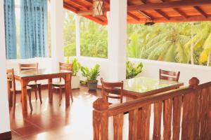 a dining room with a table and chairs and windows at Supun Villa in Bentota