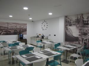 a dining room with tables and chairs and a clock on the wall at Hotel Room in Pontevedra