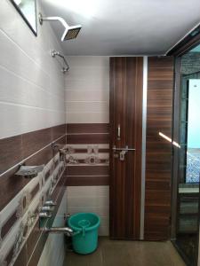uma casa de banho com uma porta de madeira e um balde verde em Suja Home Stay em Hampi