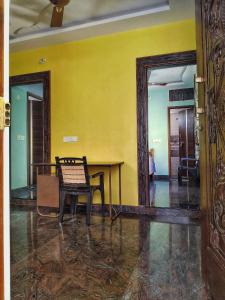 um quarto amarelo com uma mesa e um espelho em Suja Home Stay em Hampi