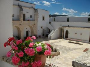 a white vase filled with flowers next to a building at Masseria Casamassima agriturismo in Ostuni