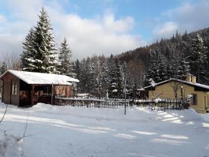 a cabin in the snow with a fence and trees at Zbójnicki Ostęp in Stronie Śląskie