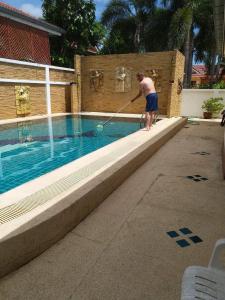 a man playing with a hose in a swimming pool at Baan Chockchai 3 in Bang Sare