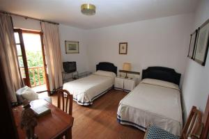 a bedroom with two beds and a desk and a table at El Berdial in San Esteban de Pravia