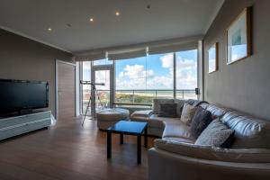 ein Wohnzimmer mit einem Sofa und einem Flachbild-TV in der Unterkunft Panoramic & Modern apartment with sea view in Bredene