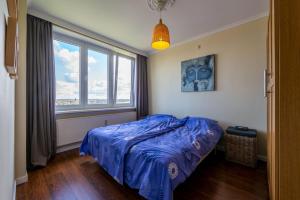 ein Schlafzimmer mit einem blauen Bett und einem Fenster in der Unterkunft Panoramic & Modern apartment with sea view in Bredene