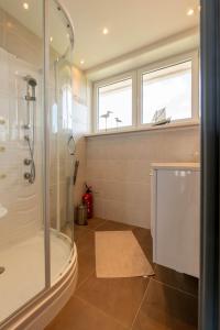 ein Bad mit einer Dusche und einer Glasduschkabine in der Unterkunft Panoramic & Modern apartment with sea view in Bredene