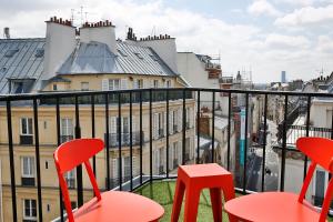 uma varanda com cadeiras vermelhas e vista para a cidade em Hôtel Joséphine by Happyculture em Paris