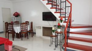 a living room with a staircase and a table and chairs at Diodeth's Holiday Apartment in Butuan
