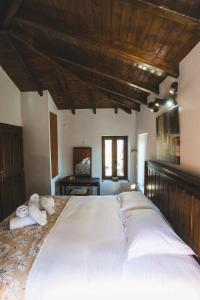 a large white bed in a bedroom with a wooden ceiling at Litheon House in Synikia Mesi Trikalon