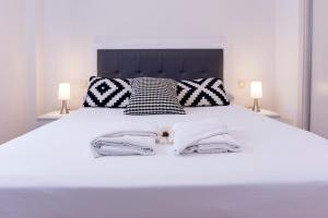 a bedroom with a white bed with black and white pillows at Livemalaga Ventura & Parking in Málaga