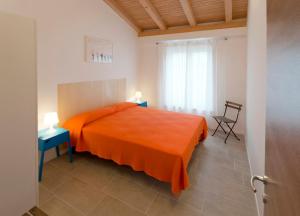 een slaapkamer met een oranje bed en een stoel bij Giotto Holiday Houses in Vrsi