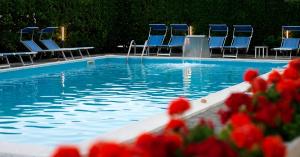 a swimming pool with blue chairs and a fountain at Hotel Life in Rimini
