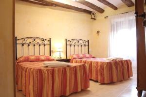 a bedroom with two beds with red and orange sheets at Casa Rural "La Bardena Blanca I " in Arguedas