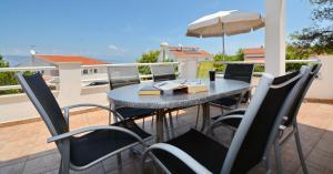 ein Tisch mit Stühlen und einem Sonnenschirm auf einer Terrasse in der Unterkunft Apartmani Cesarec in Basina