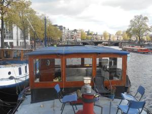 ein Boot mit einem Tisch und Stühlen auf dem Wasser in der Unterkunft Waterloo square river vieuw houseboat in Amsterdam