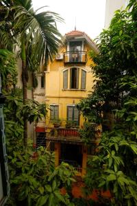 a yellow building with a balcony and a palm tree at French-styled house in Hanoi