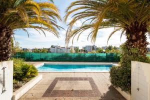 a swimming pool in a yard with palm trees at Escapade Bordeaux, tram et supermarché au pied in Mérignac