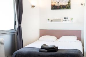 een slaapkamer met een bed met twee kussens erop bij Escapade Bordeaux, tram et supermarché au pied in Mérignac +18 foto's
