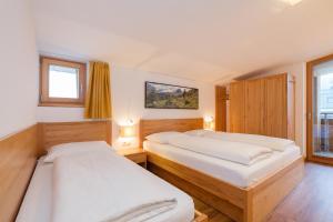 a bedroom with two beds and two windows at Residence Aichner in Brunico