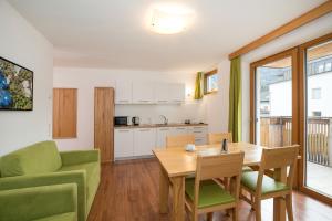 cocina y sala de estar con mesa de madera y sillas en Residence Aichner en Brunico