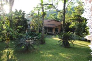 una casa con un patio con palmeras en Pousada Sitio Araribá, en Ubatuba