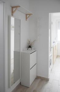 a white kitchen with a dresser and a mirror at White Almond Apartment in Budapest