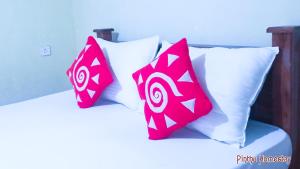 two red and white pillows on a bed at Pinthu Home Stay in Sigiriya