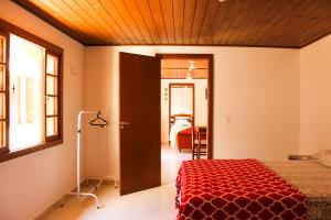 um quarto com uma cama com um edredão vermelho em Recanto Dos Coqueiros em Florianópolis