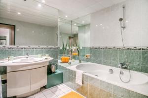 a bathroom with a tub and a sink and a mirror at Hôtel Le Maxime - Best Western Signature Collection in Auxerre