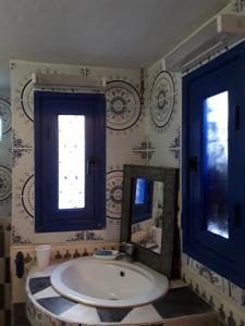a bathroom with a sink and two mirrors at La Maison Bleue in Sidi Ifni
