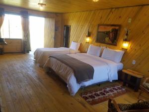 a bedroom with two beds in a room with wooden walls at Pousada Serra Catarinense in São Joaquim