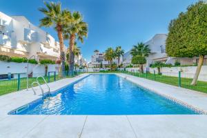 uma piscina em frente a um edifício com palmeiras em Apartamento en Urbanizacion Hacienda Golf Islantilla na Isla Cristina