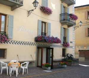 a table and chairs in front of a building with flowers at Meublé Albergo Dante in Bormio