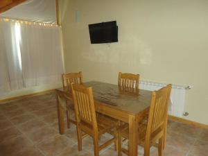 a dining room table with chairs and a television on the wall at Unquehue Apartamentos Dormis in Villa La Angostura