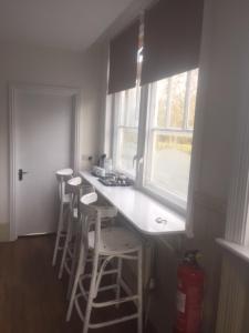 a kitchen with a counter with stools and a window at Good Intent Rooms in Waltham Abbey