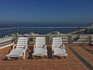 a group of white lounge chairs on a patio overlooking the ocean at Departamento Alto Libertad Meseta Coraceros in Viña del Mar