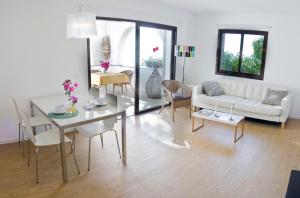 a living room with a white couch and a table and chairs at ALCUDIA-VIDA SANA-PRIMERA LINEA DE MAR in Alcudia +9 photos