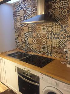 a kitchen with a sink and a tile wall at Apartamentos El Greco in Toledo +8 photos