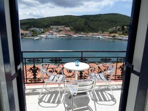 a table and chairs on a balcony with a view of the water at Nicolas Rooms in Fiskardo